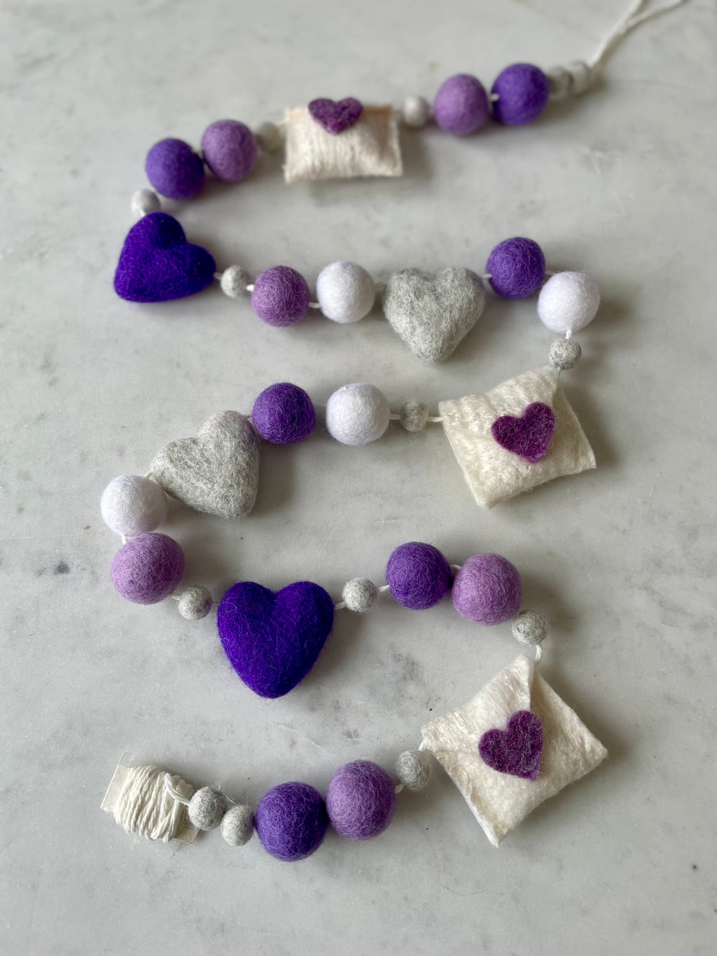 Decorative felt wool garland with purple hearts and love letters for Valentine's day.