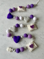 Decorative felt wool garland with purple hearts and love letters for Valentine's day.