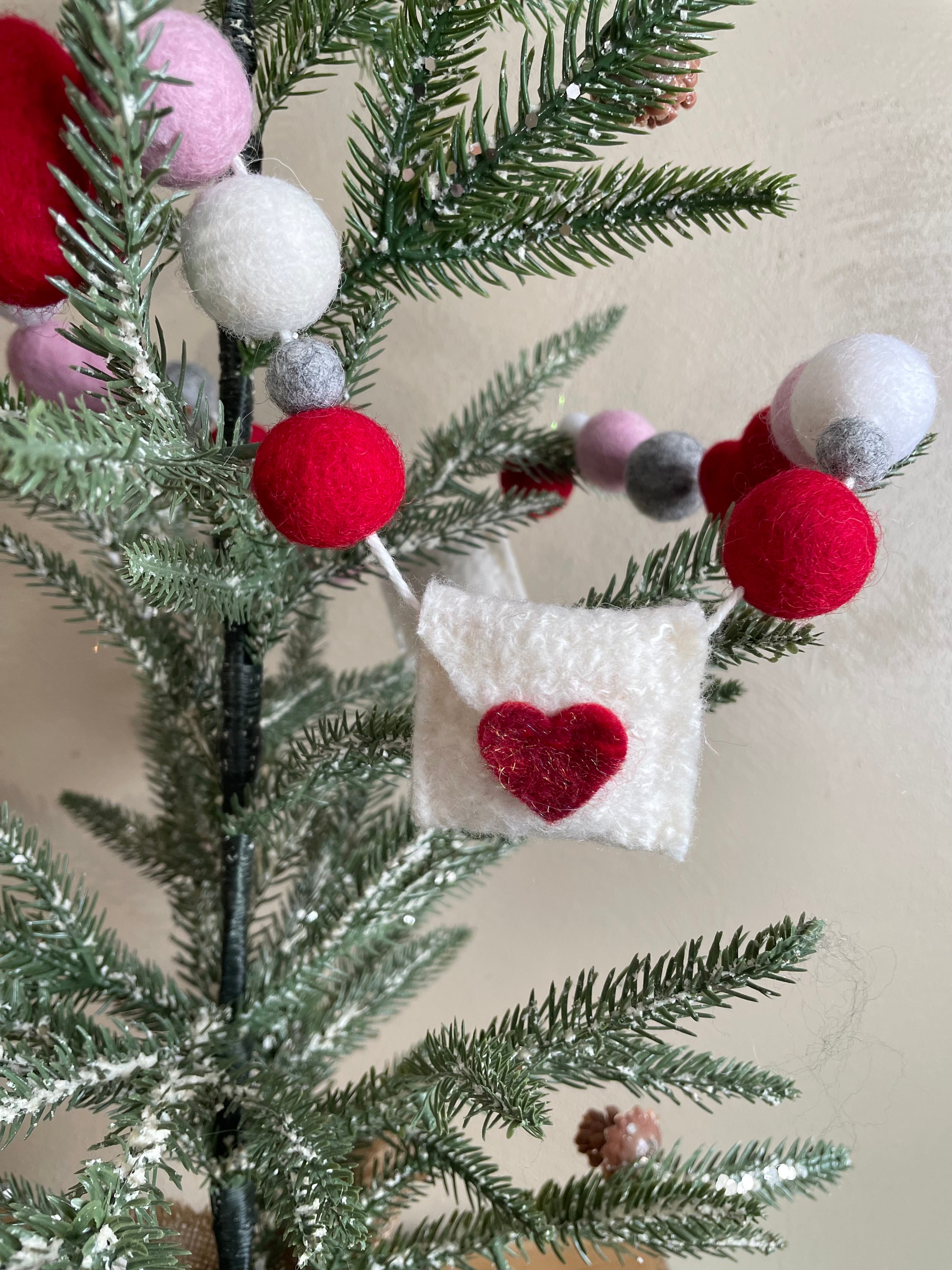 Decorative felt wool garland with red and pink hearts and love letters for Valentine's day.